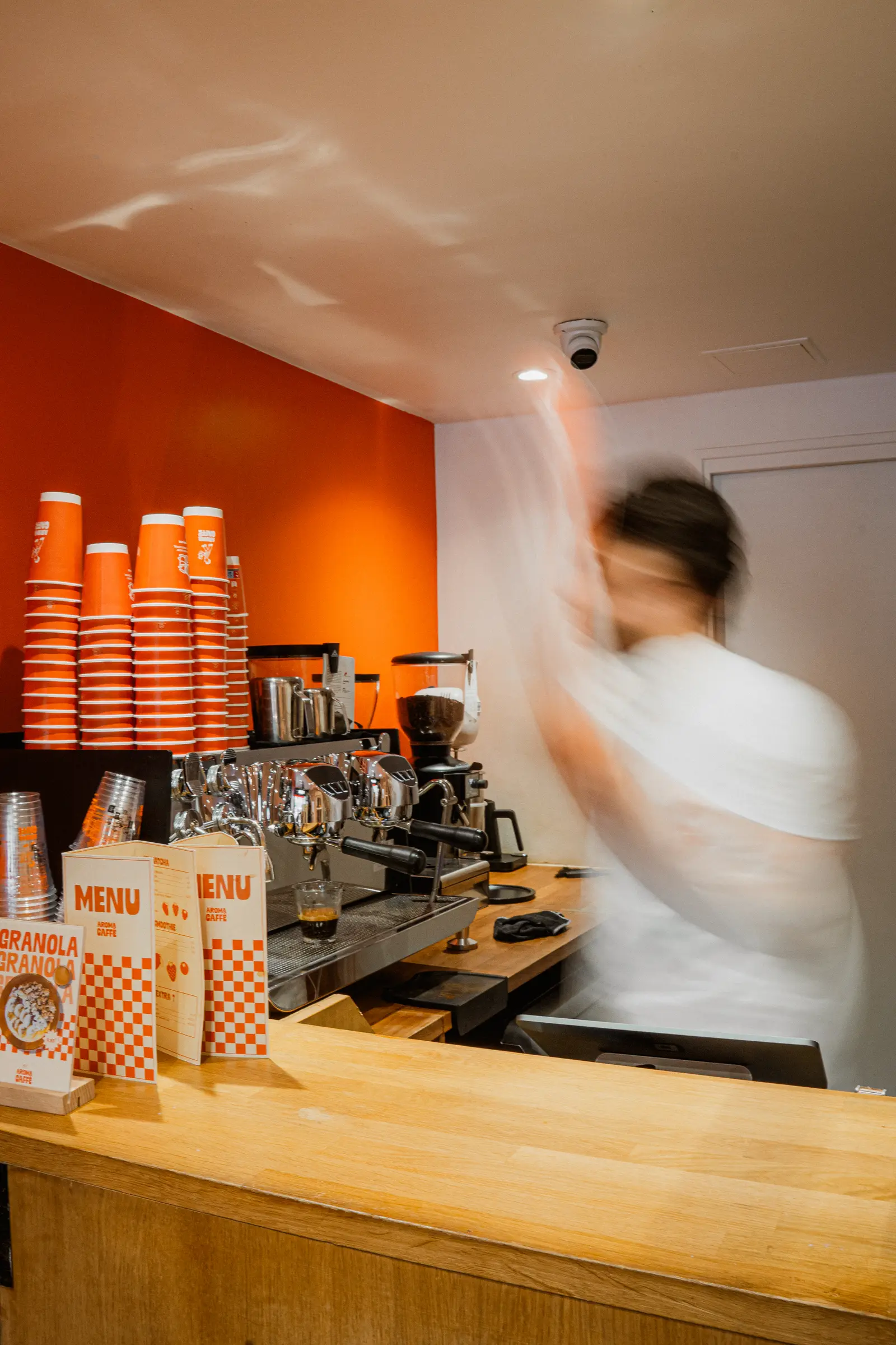 Barista au comptoir orange du coffee shop Aroma Caffè