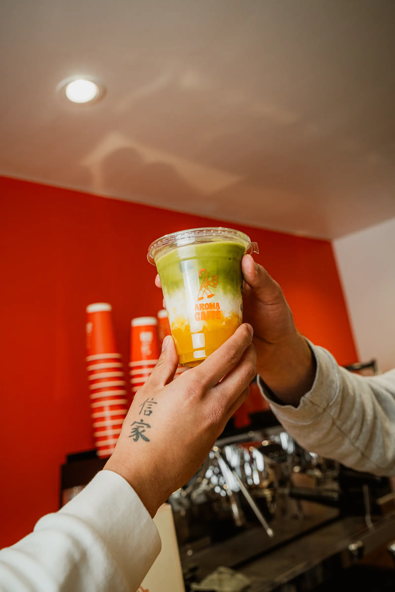 Matcha latte tenu devant la machine à café d'Aroma Caffè