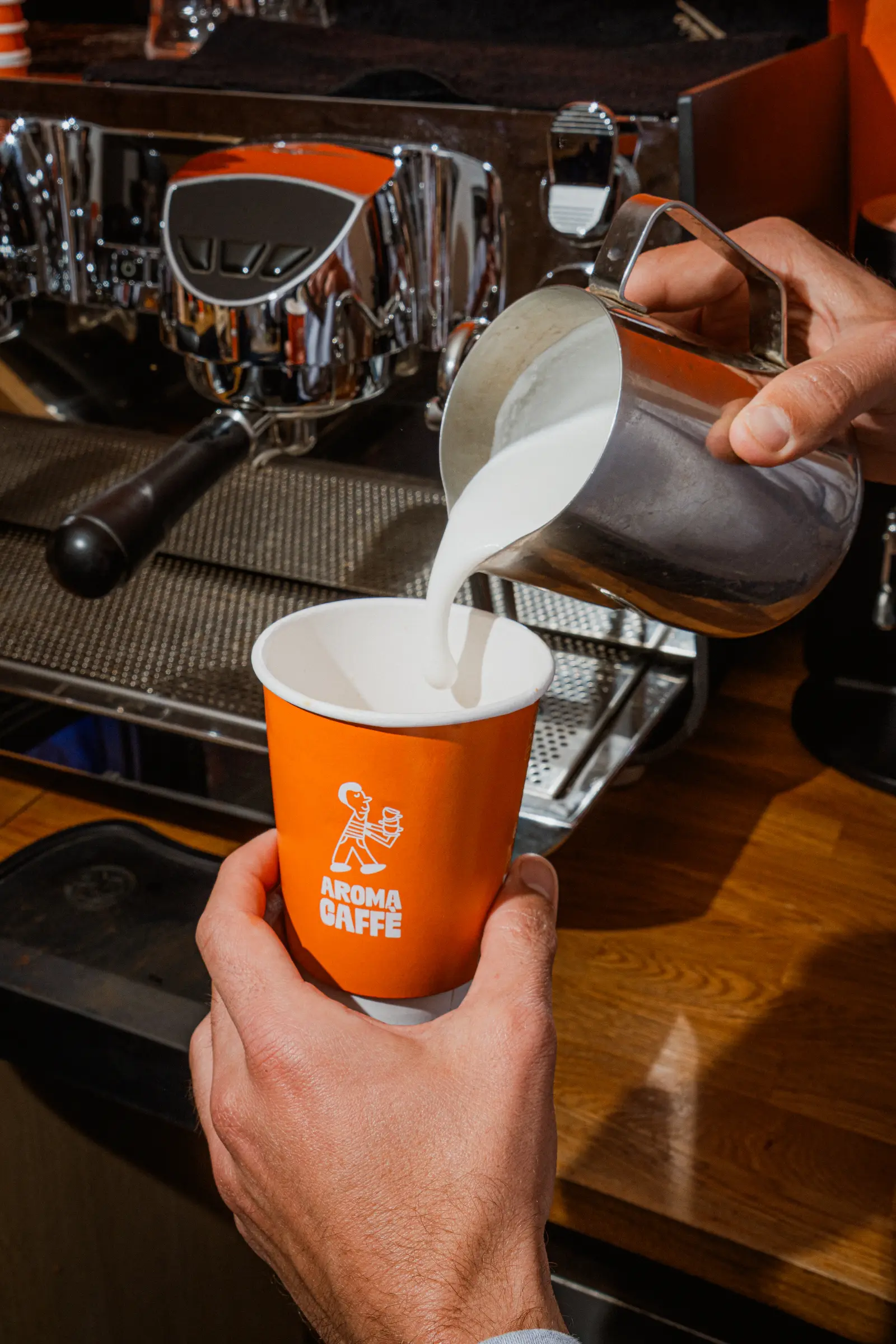 Versement du lait dans un gobelet de café Aroma Caffè